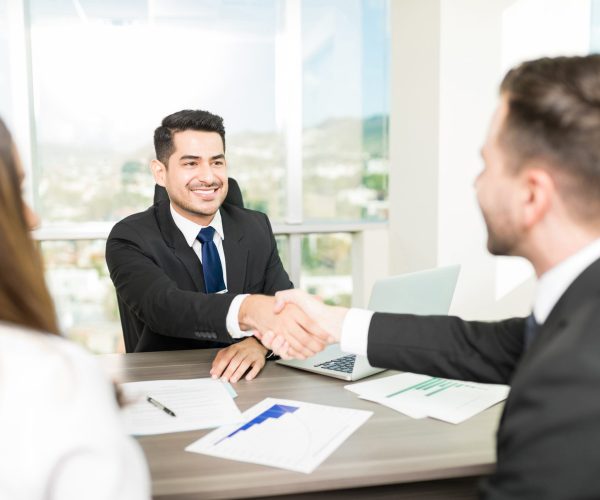Financial adviser sealing a deal with clients at desk in office